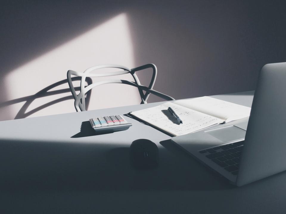A tidy desk with a laptop, notebook and calculator